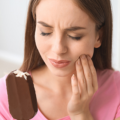 Young woman with sensitive teeth and cold ice-cream at home