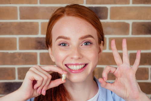 Smiling Teenage Girl holding a wisdom tooth